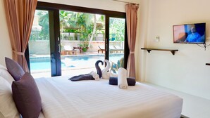 Une chambre d’hôtel avec un lit, des oreillers, une télévision et une vue sur une piscine.