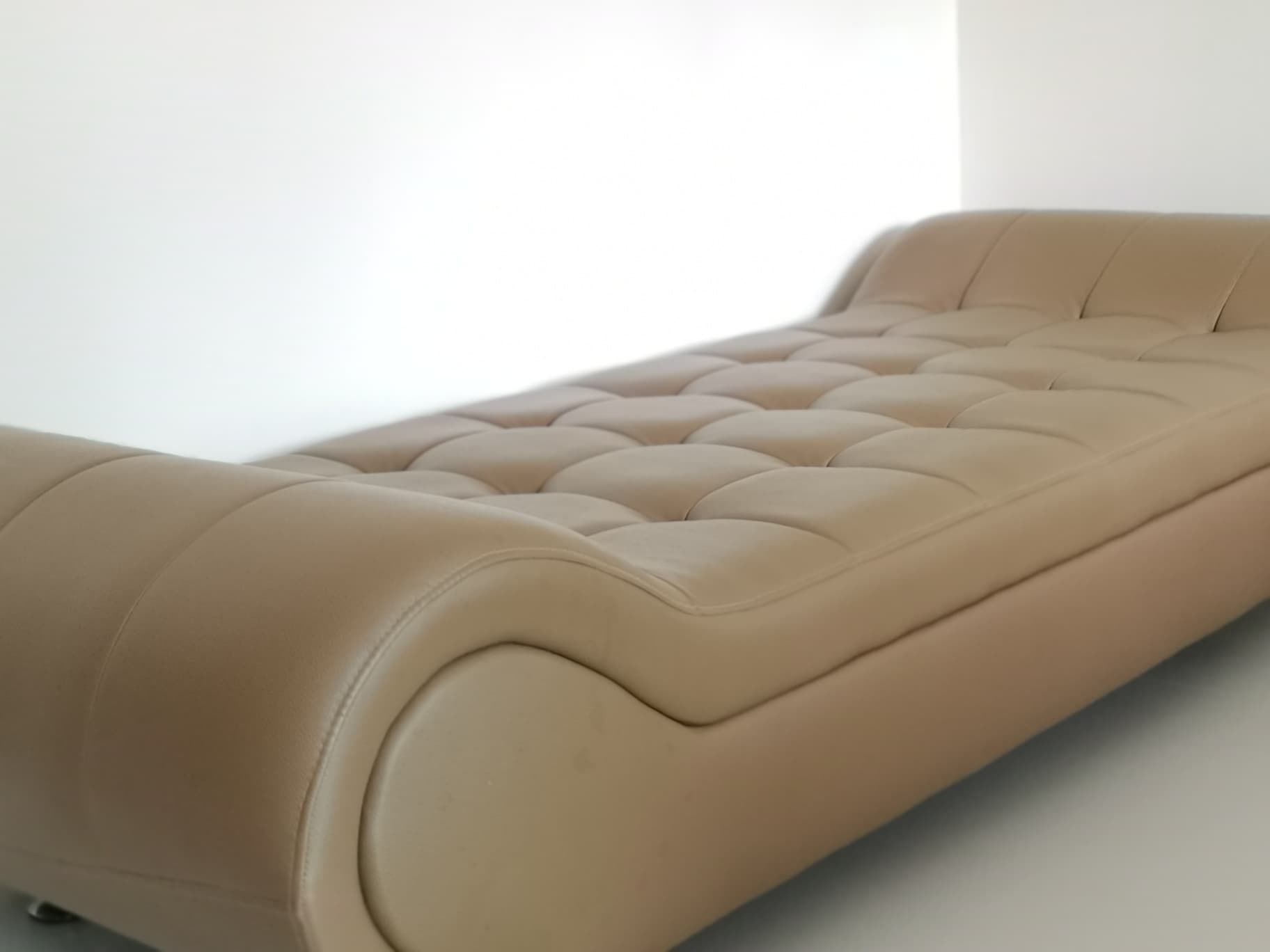 Un lit simple avec une tête de lit capitonnée et un pied de lit incurvé.