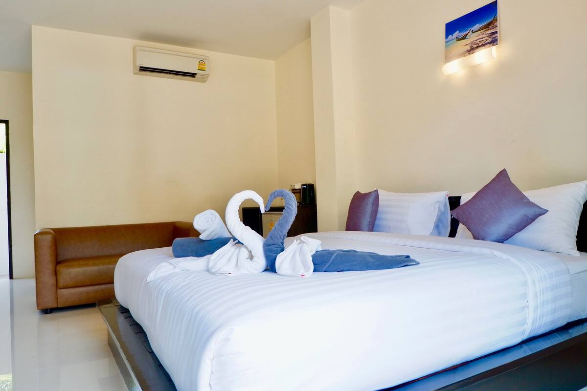 Une chambre d’hôtel avec un grand lit, un canapé marron et un climatiseur fixé au mur.