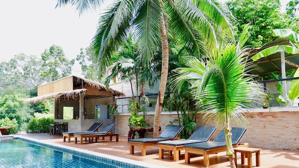 Un espace piscine avec des chaises longues et une petite structure en bois.