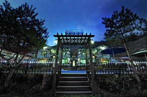 A hotel entrance with a wooden archway, steps leading up to a covered area, and a sign above the archway.