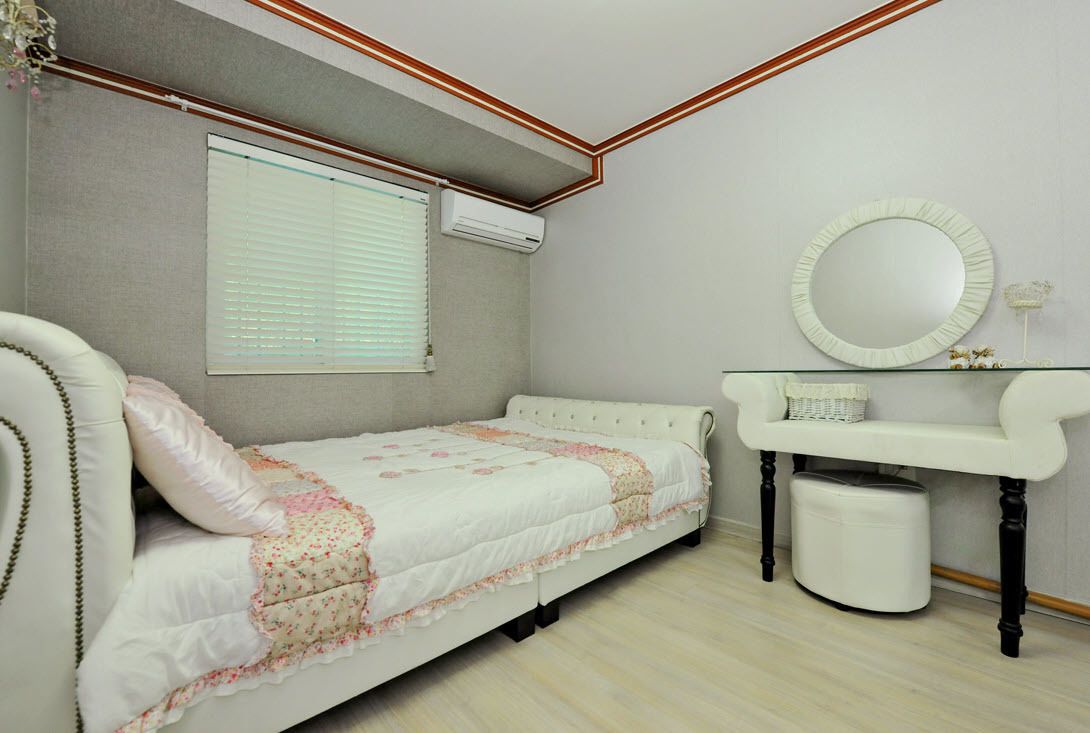 Een slaapkamer met een bed, een kaptafel met spiegel en een airconditioning.
