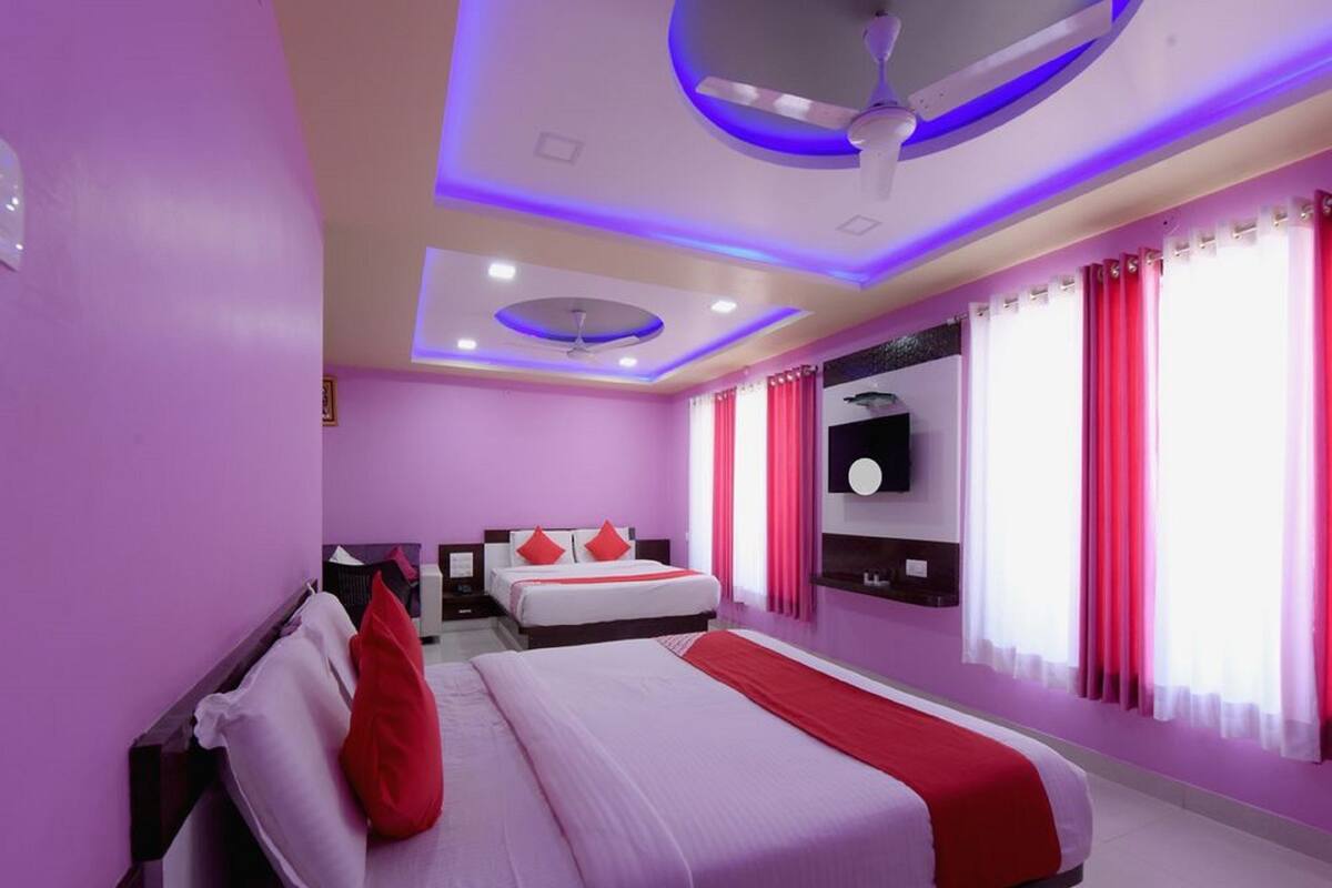 A modern hotel room with a large bed, a ceiling fan, and a TV mounted on the wall.