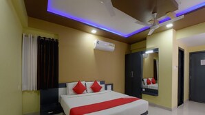 A hotel room with a bed, a ceiling fan, an air conditioning unit, a mirror, and a wardrobe. - Hotel Atithi Bhawan by Sky Stays (Nathdwara)