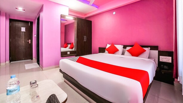 A hotel room with a large bed, a ceiling fan, a wardrobe, and a bedside table with a bottle and glasses. - Hotel Atithi Bhawan by Sky Stays (Nathdwara)