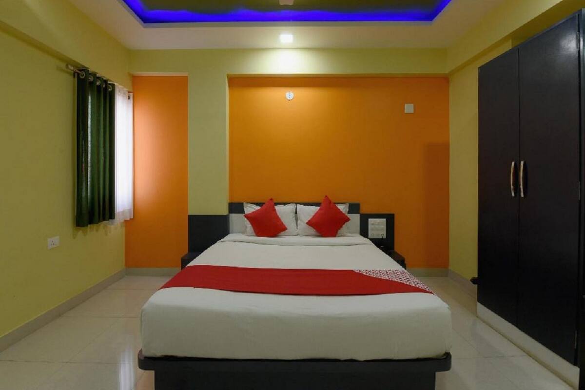 A bedroom with a bed, a wardrobe, and a ceiling with blue lighting.