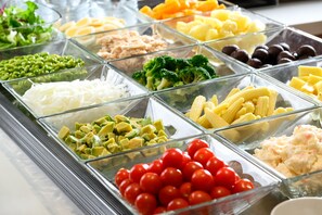 Un buffet proposant une variété de plats, notamment des légumes, des fruits et des pâtes.