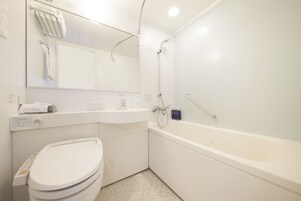 A modern bathroom with a toilet, sink, mirror, and bathtub.