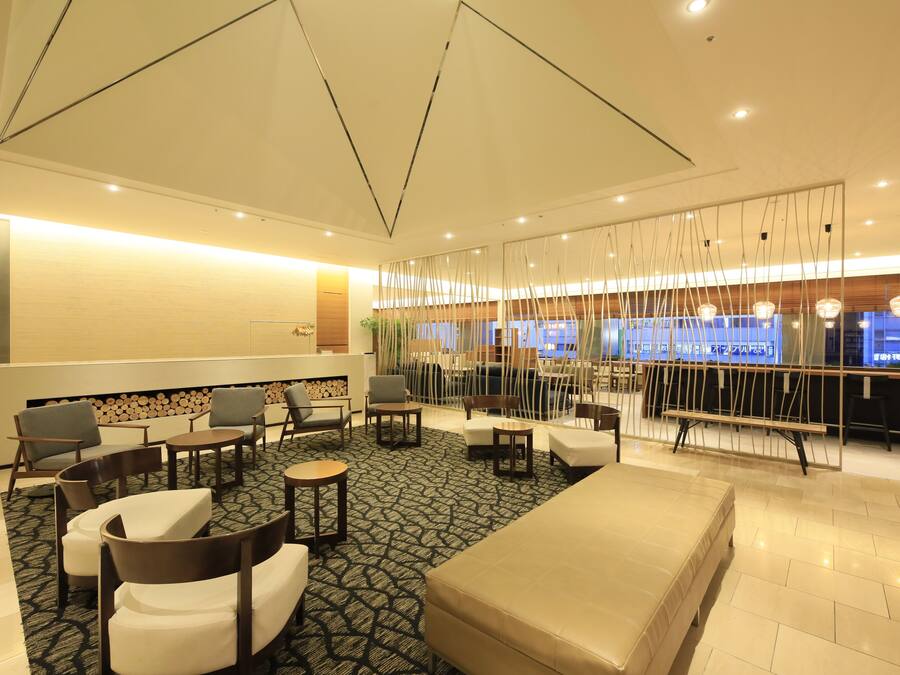 En modern hotellobby med en sittgrupp, en receptionsdisk och utsikt över poolområdet.