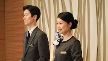 Two individuals standing in front of a curtain.