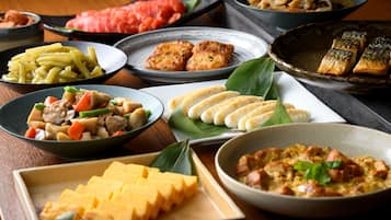 A variety of dishes on a table, including what appears to be a bowl of soup, a plate of noodles, and several other dishes with different ingredients.