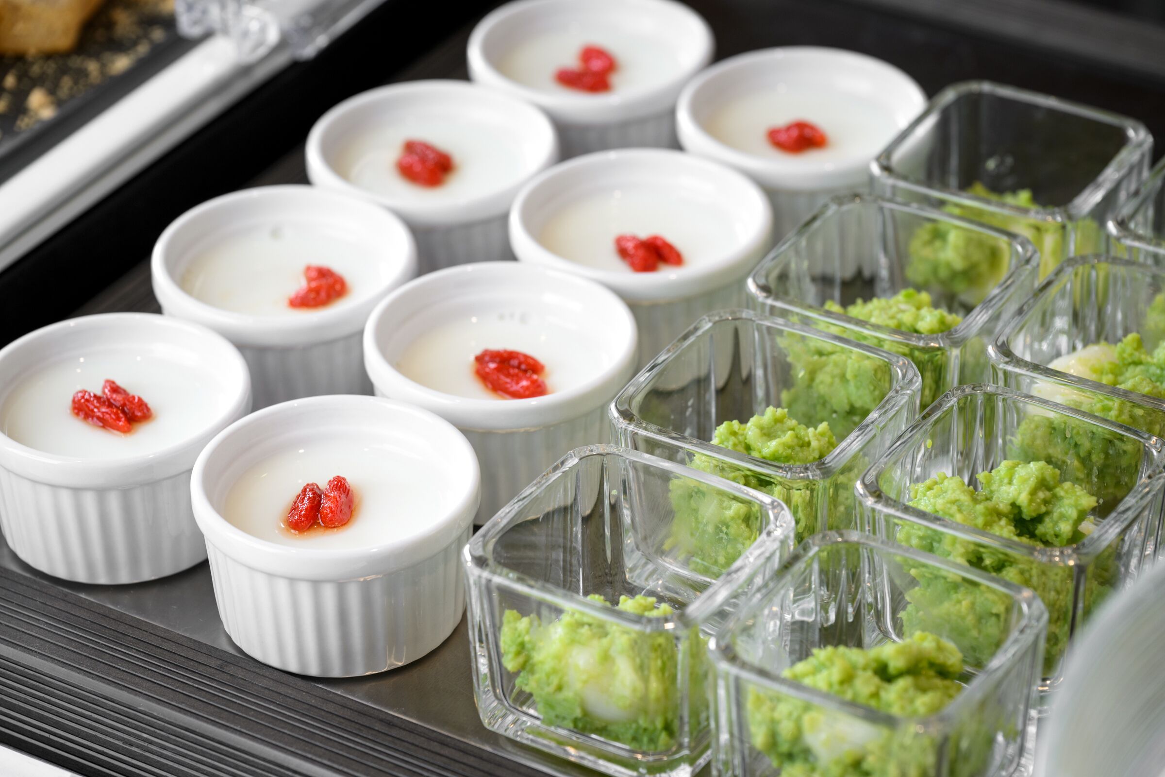 A tray of desserts with white and green portions, some topped with red.