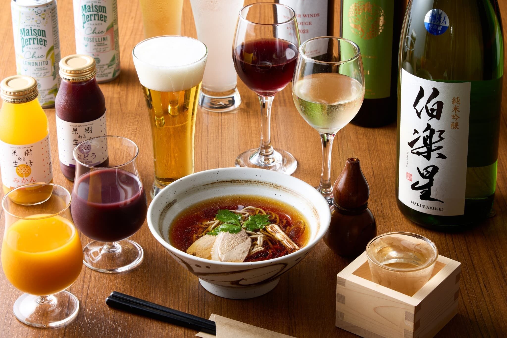 Una mesa con diversas bebidas, incluyendo botellas, vasos y un tazón de sopa.