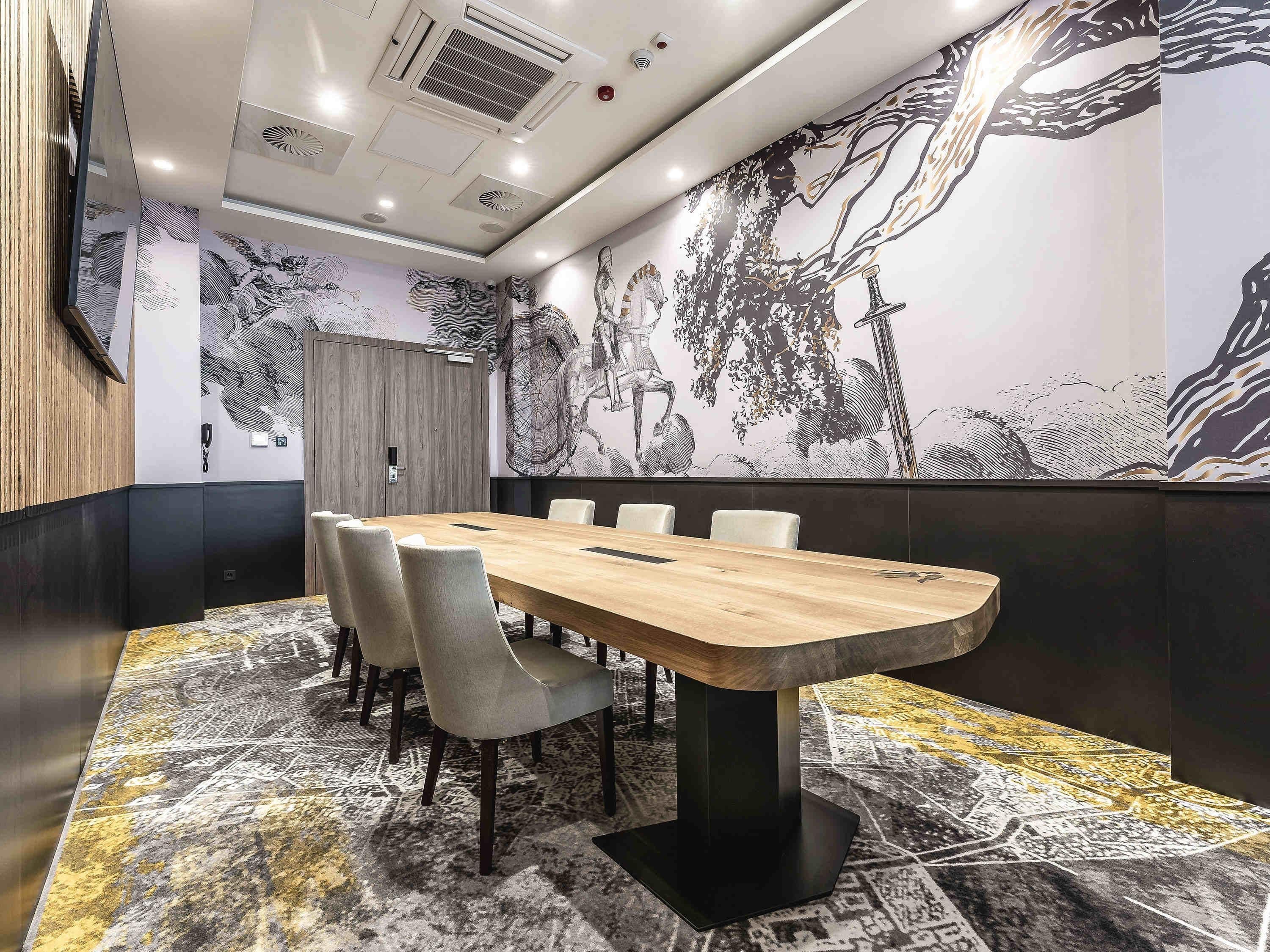 A conference room with a long table, chairs, and a patterned carpet.