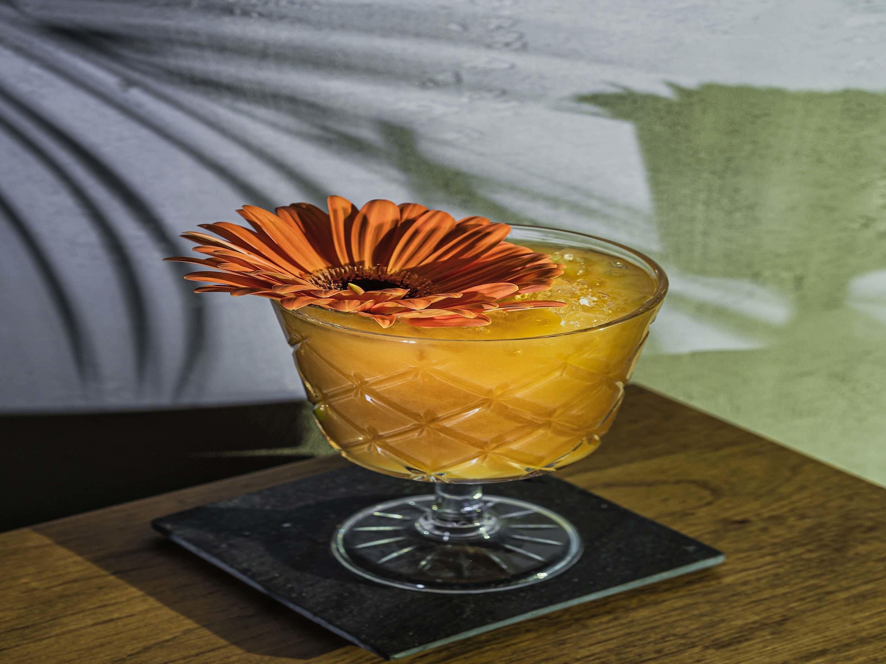 Um copo de coquetel com uma flor decorativa sobre um apoio.