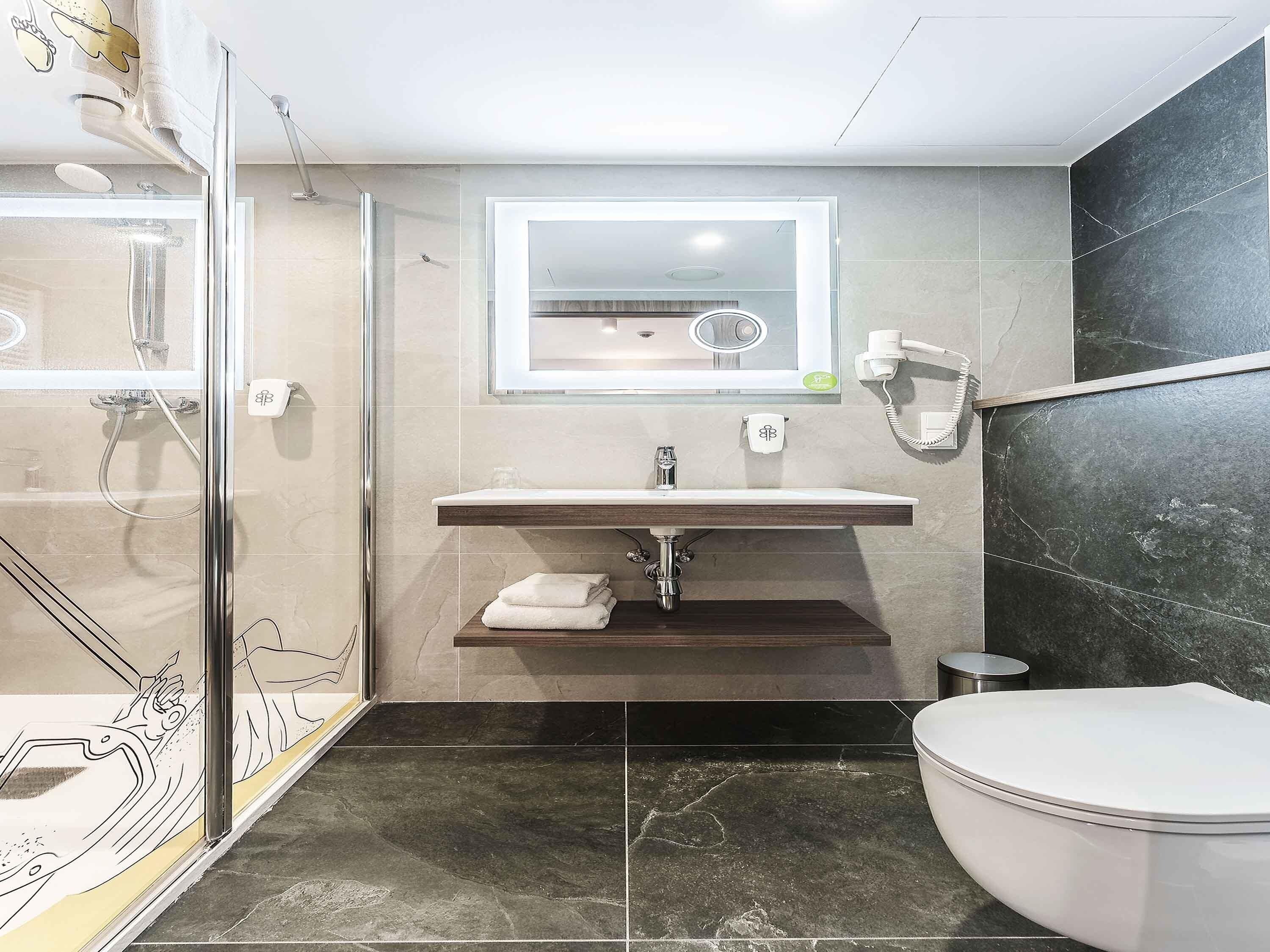 A modern bathroom with a glass shower enclosure, a vanity with a mirror, and a toilet.