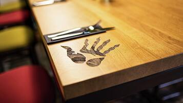 Una mesa de madera con un diseño de huella de mano, un par de tijeras y una planta en maceta.