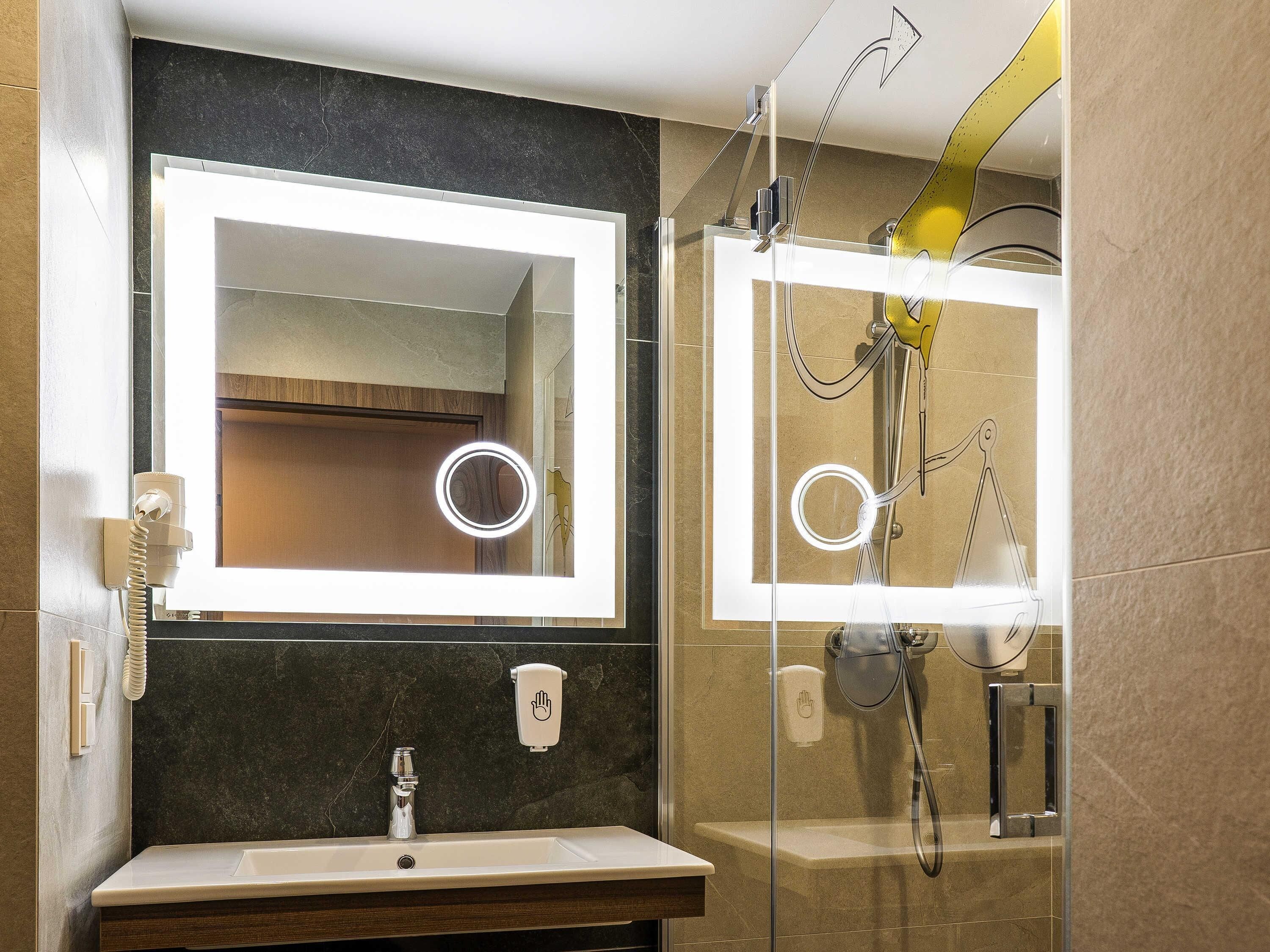 Un baño con espejo, lavamanos y ducha.