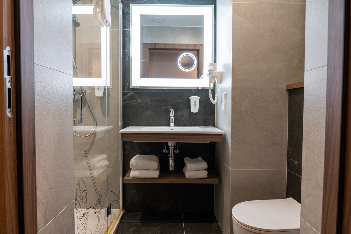 A modern bathroom with a vanity, mirror, and toilet.