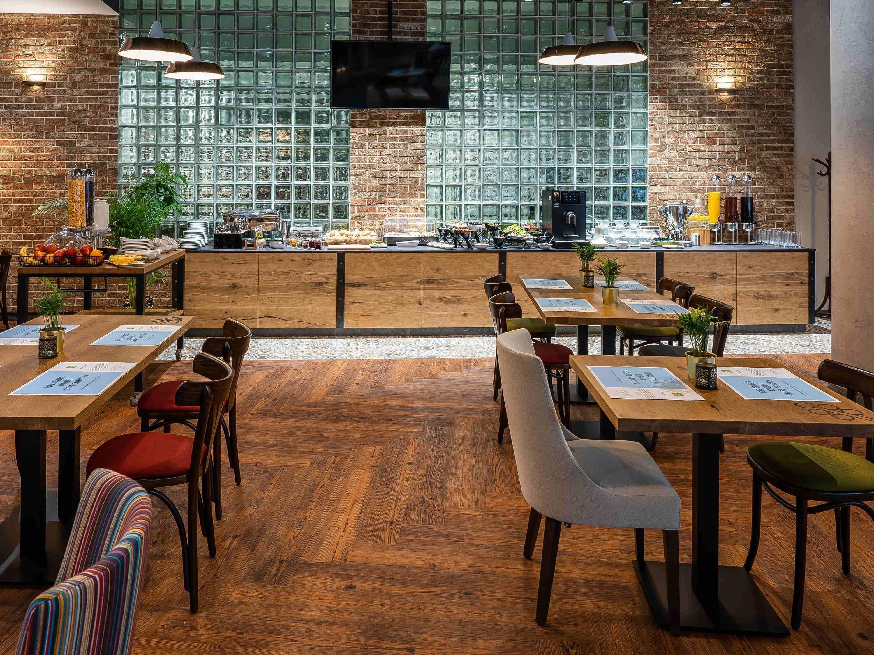 Een restaurant met houten tafels en stoelen, een bakstenen muur en een groot raam met uitzicht.