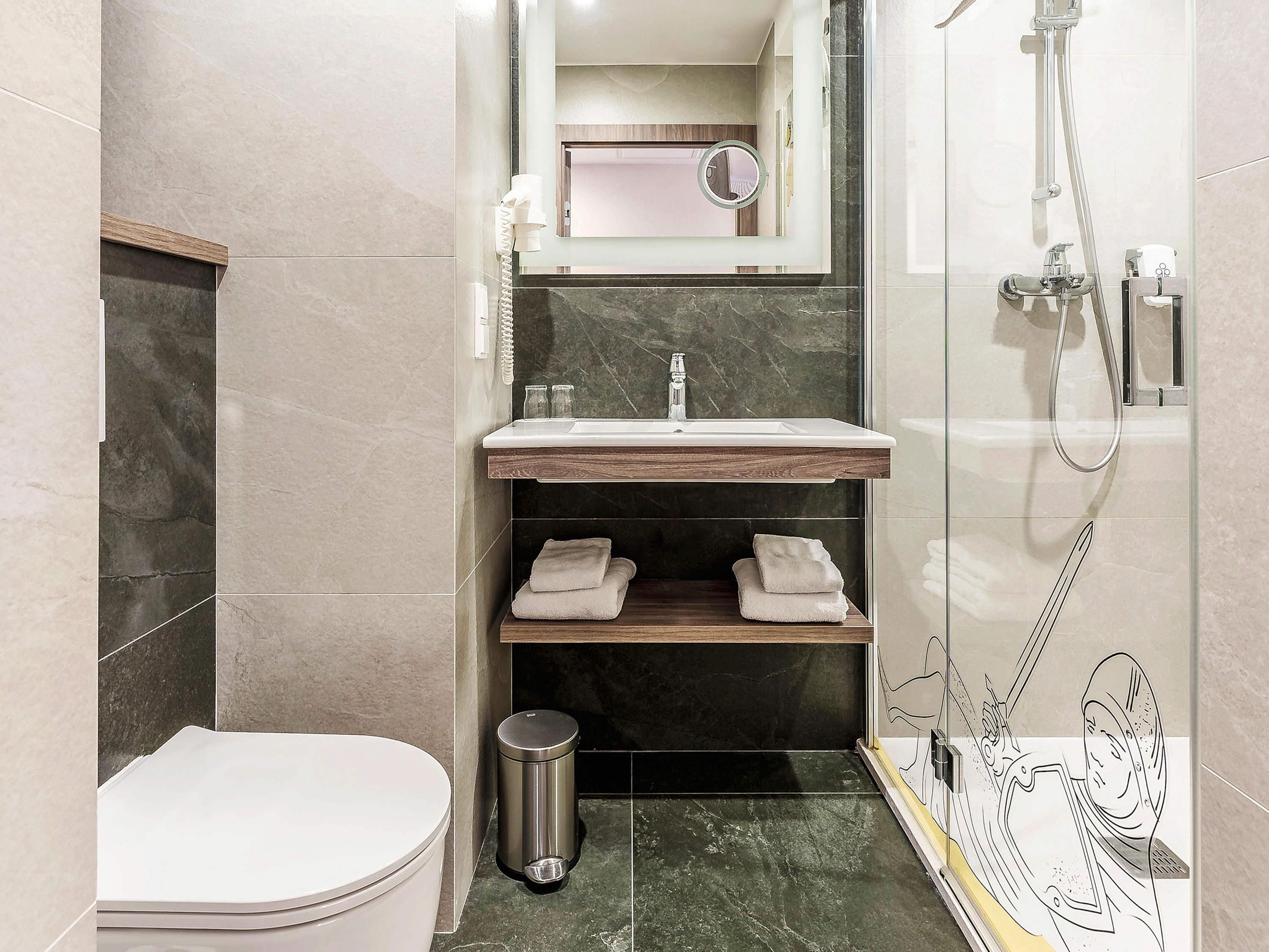A compact bathroom with a toilet, sink, and shower.