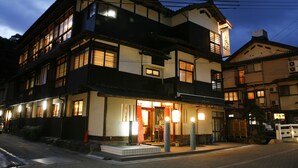 A traditional Japanese building with multiple windows and a well-lit entrance. - Hanamandara (Toyooka)