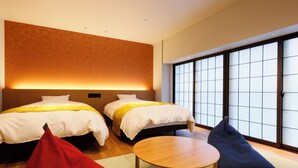 A hotel room with two beds, a wooden table, and a large window with a view. - Hanamandara (Toyooka)