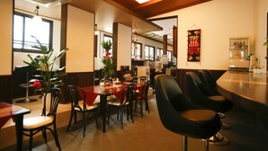 A restaurant interior with a long counter, multiple chairs, a table with a red tablecloth, and a hanging decoration. - Hanamandara (Toyooka)