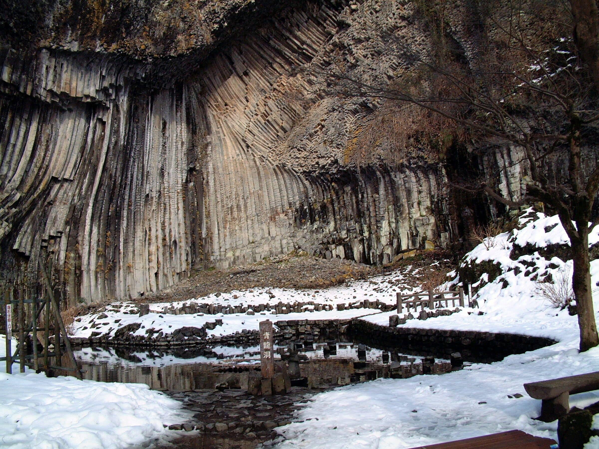 A natural rock formation with a wooden walkway and a small pond.