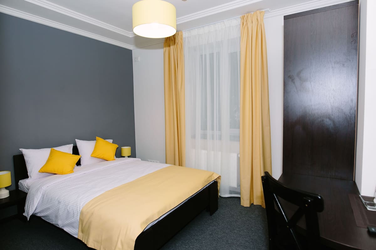 A hotel room with a bed, a desk, and a chair.