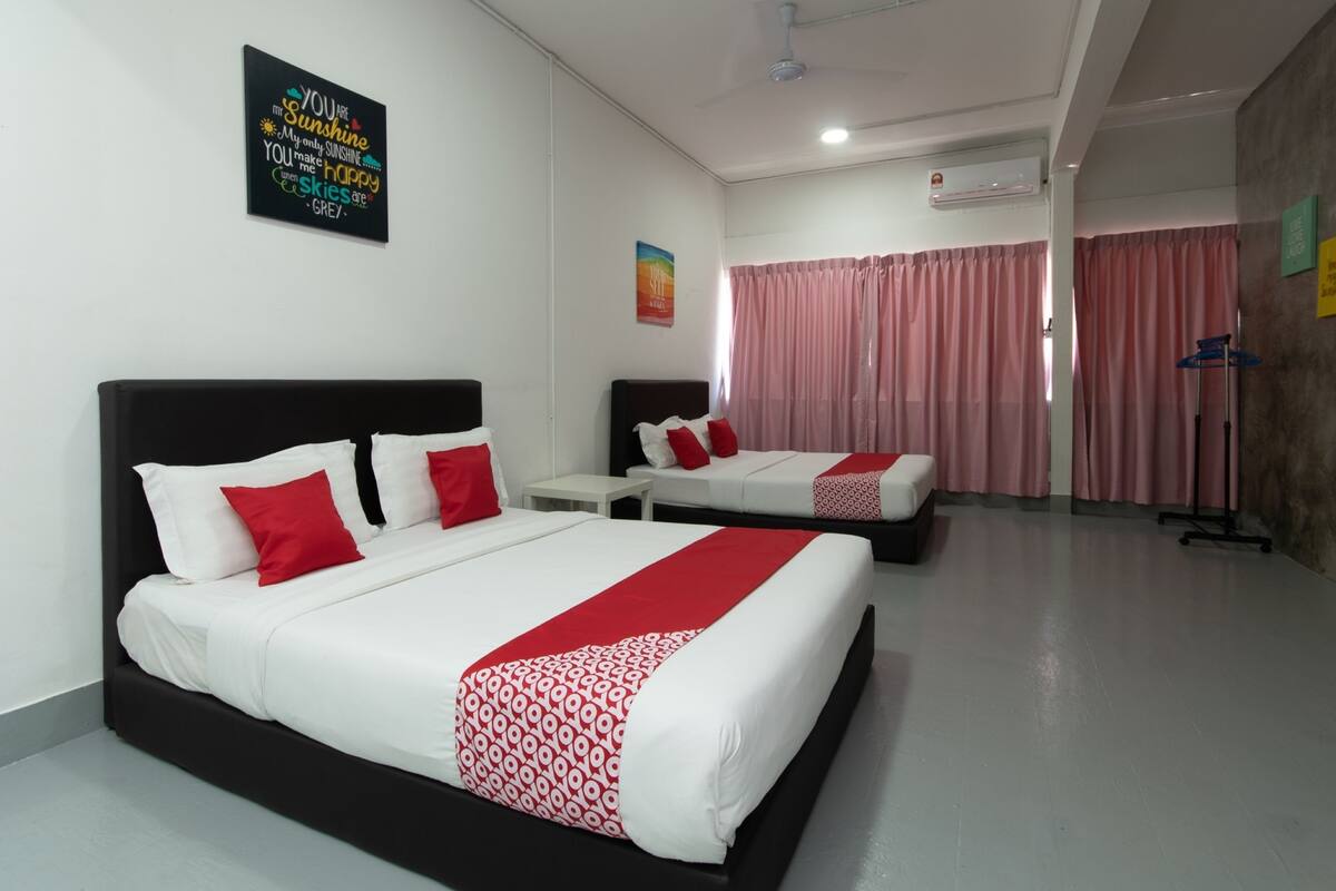 Une chambre d’hôtel avec deux lits, un ventilateur de plafond, un appareil de climatisation et une grande fenêtre avec des rideaux roses.