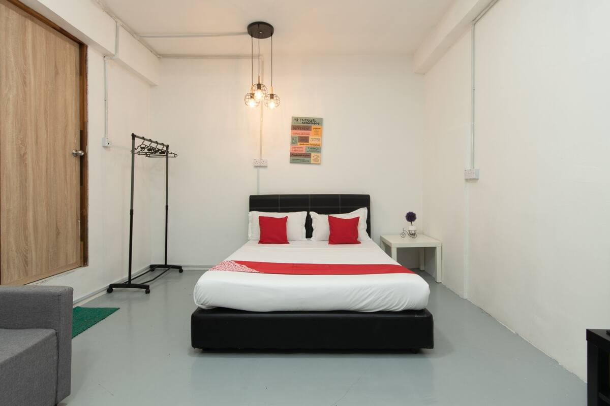 Une chambre à coucher comprenant un lit, une table de chevet, une lampe sur pied et une armoire.