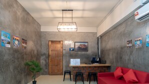 A reception area with a wooden door, a desk with a computer, a red sofa, and a potted plant. - OYO 43993 Madsuite (Kota Kinabalu)