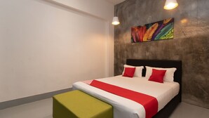 A modern hotel room with a large bed, a green ottoman, and a colorful abstract painting on the wall. - OYO 43993 Madsuite (Kota Kinabalu)