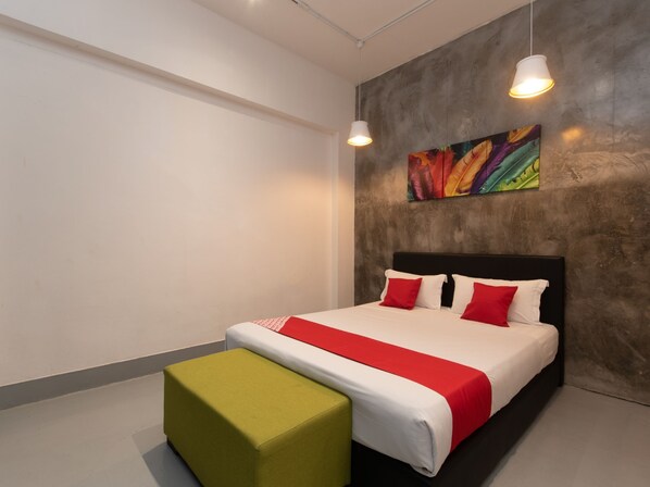 Una habitación de hotel moderna con una cama grande, un reposapiés verde y un cuadro abstracto de colores en la pared.