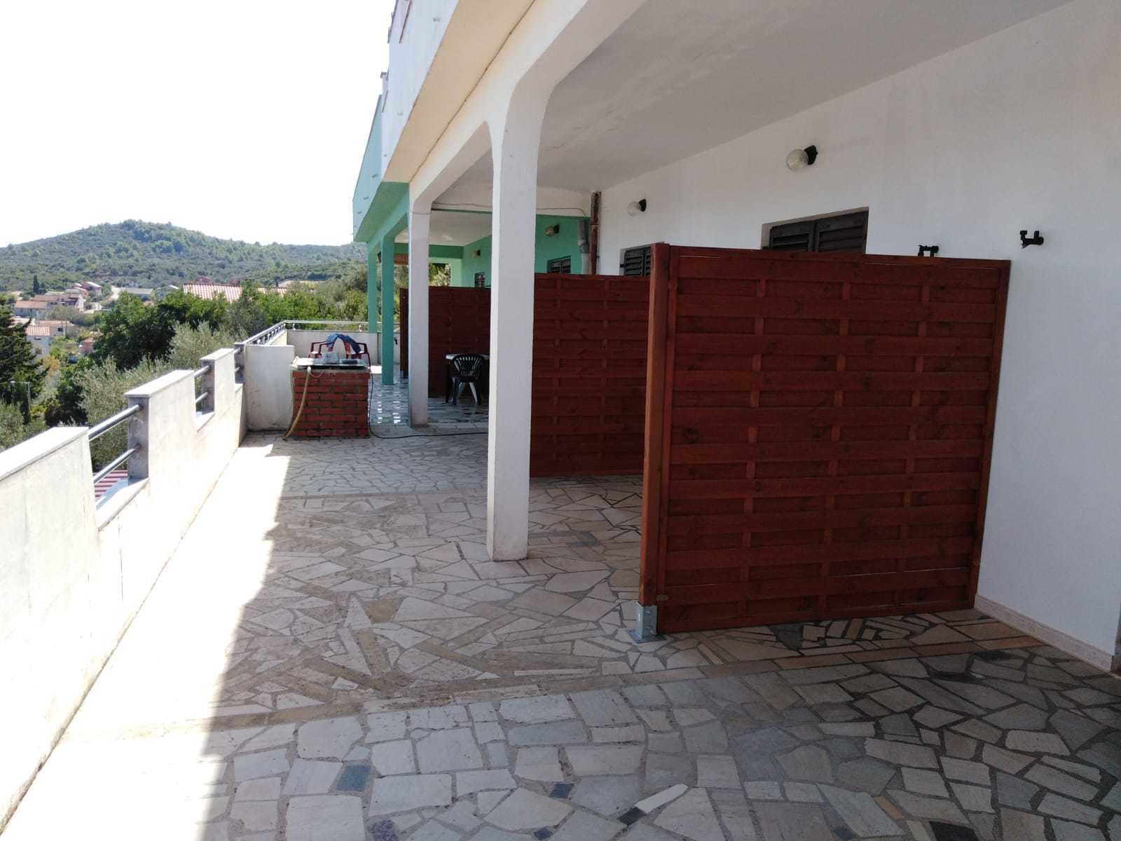A covered outdoor area with a tiled floor, a brick wall, and a metal gate.