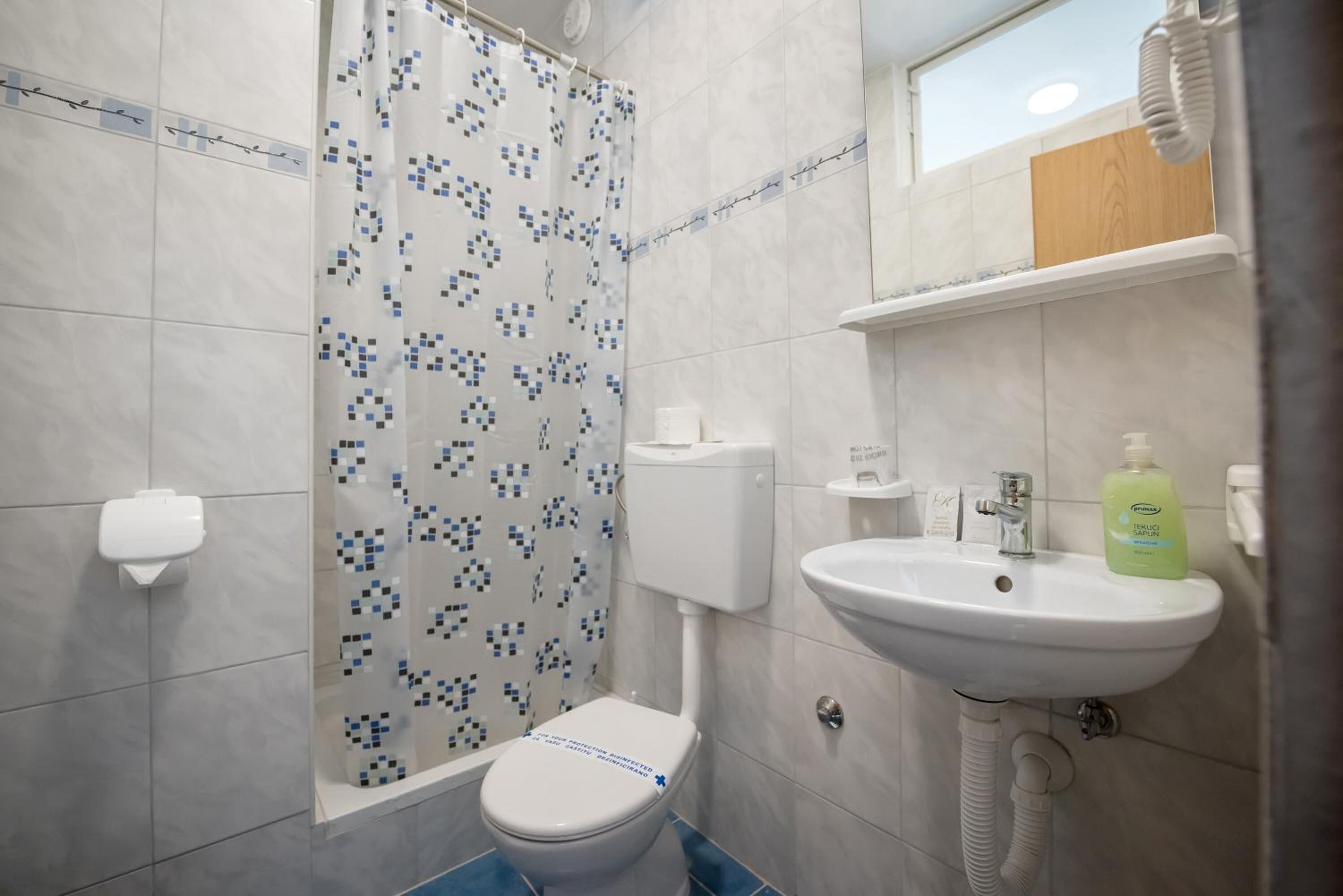 A bathroom with a toilet, shower, and sink.