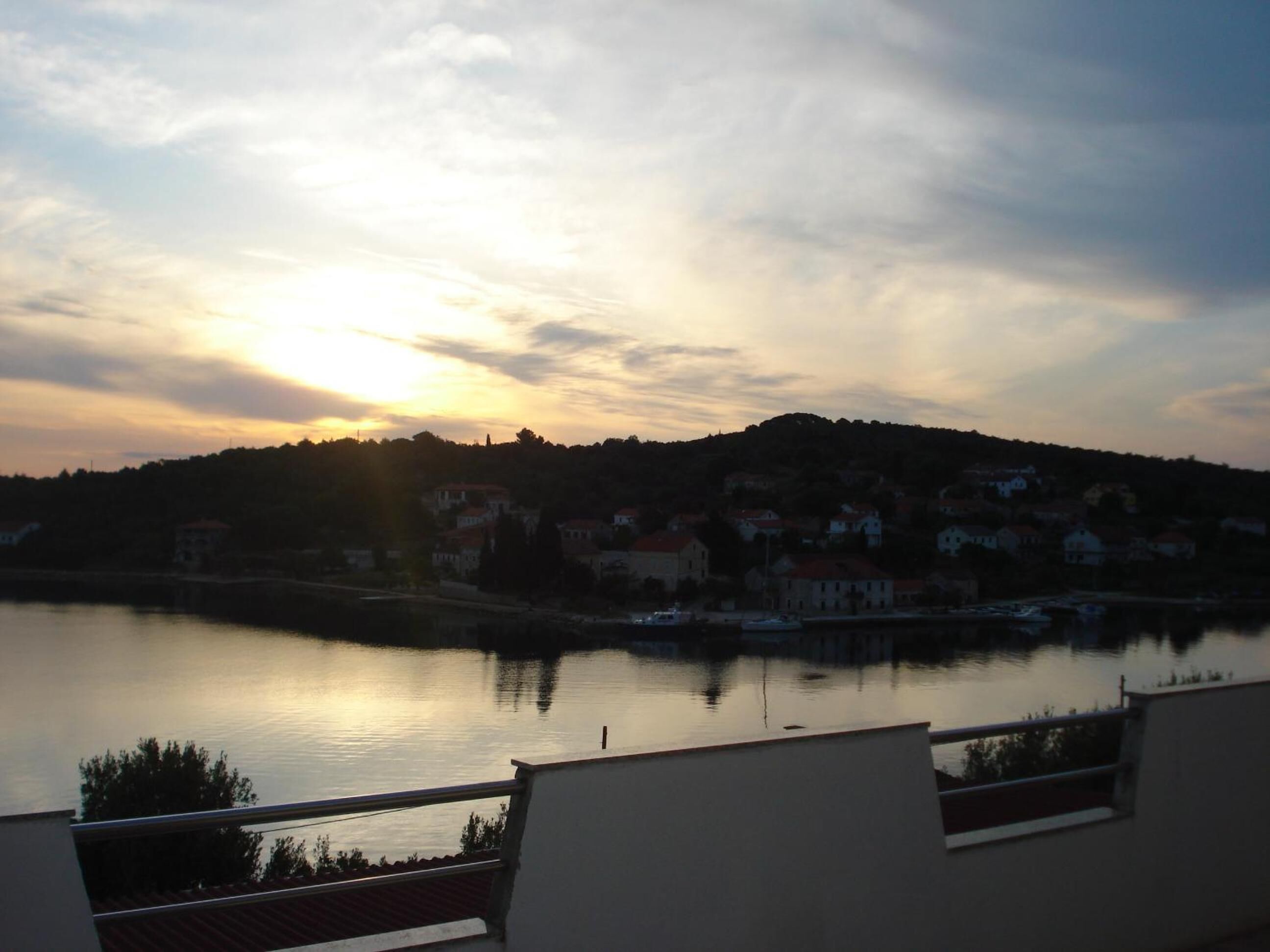 A sunset over a calm lake with buildings on the opposite shore.