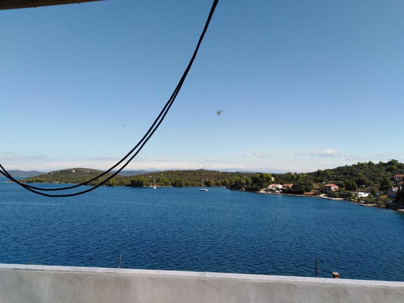 A coastal view with a clear sky, a body of water, and a distant shoreline with buildings.