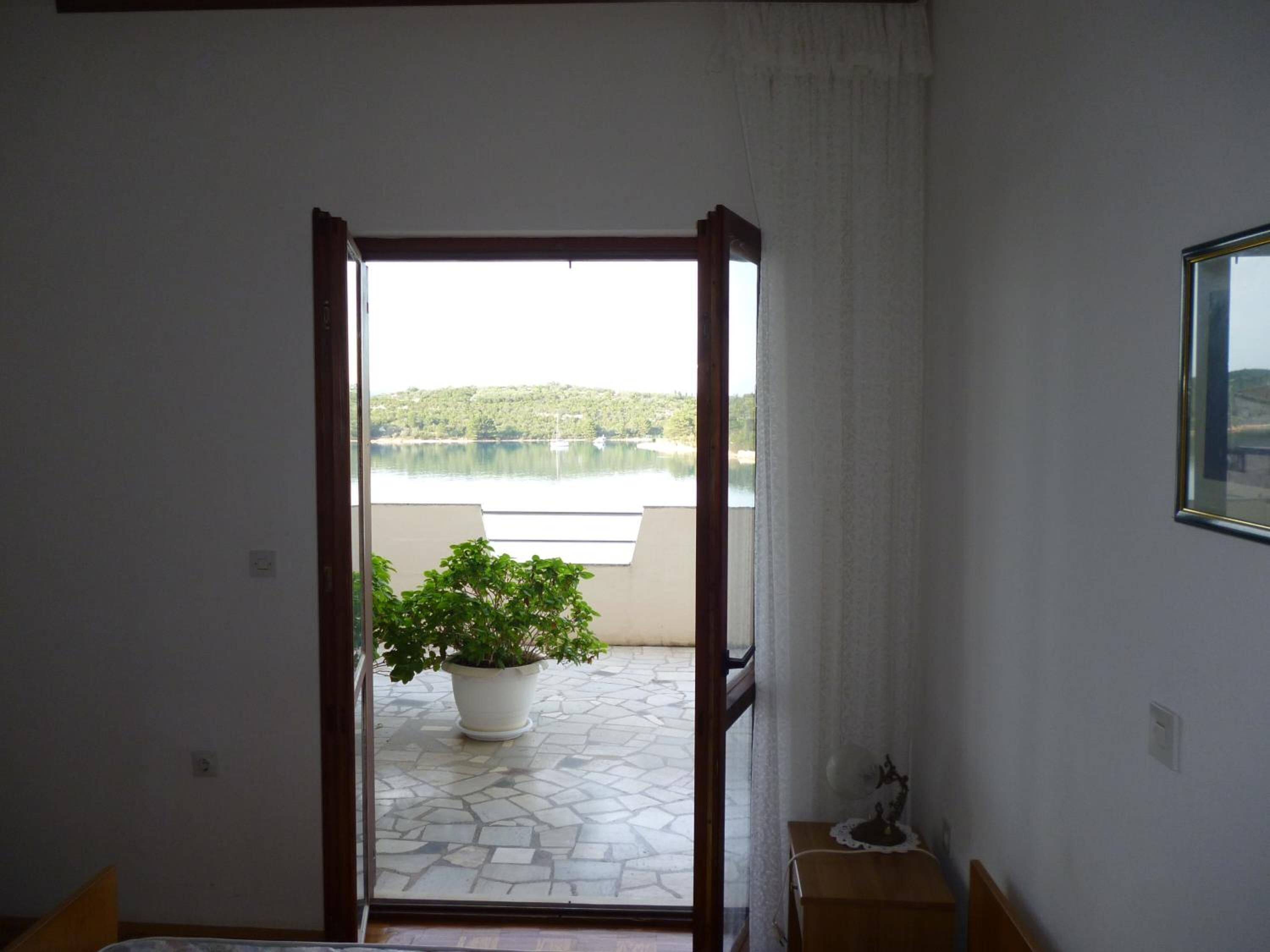 A room with a view of a lake and a balcony with a potted plant.