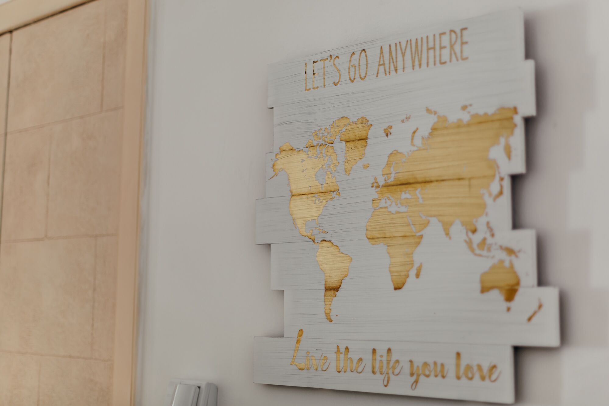 A world map with the phrase "Let's go anywhere" and "Live the life you love" on a wall.