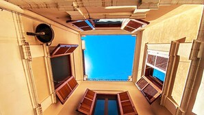 A high-ceilinged atrium with a central skylight, multiple windows with shutters, and a decorative ceiling medallion. - Casa D'Angiò (Manfredonia)