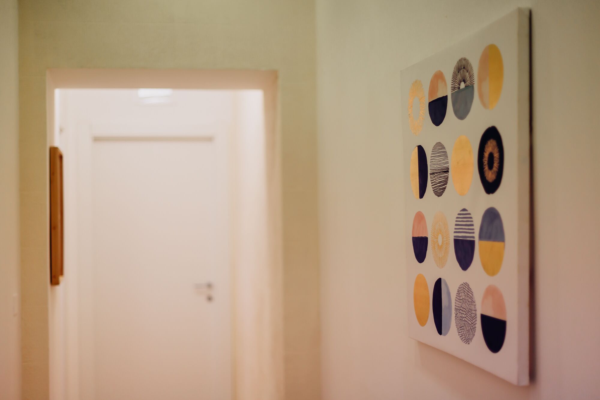 A hallway with a white door and a wall with abstract circular art.
