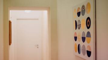 A hallway with a white door and a wall with abstract circular art.