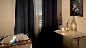 A dimly lit room with a dining table, candles, and a bottle of liquor. - Casa D'Angiò (Manfredonia)