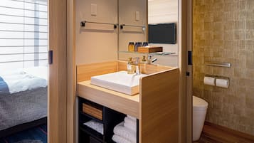 A modern bathroom with a wooden vanity, a glass shelf, a toilet, and a large mirror.