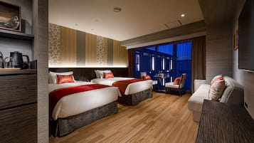 A hotel room with two beds, a sofa, a small table, and a TV.