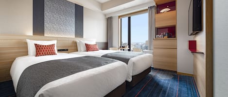 Une chambre d’hôtel avec deux lits, une télévision, une fenêtre donnant sur la ville et un minibar.