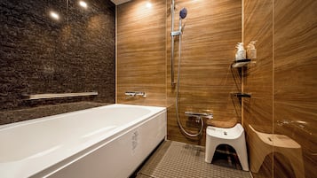 A modern bathroom with a large bathtub, a shower, and a toilet.