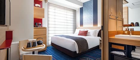 Ein modernes Hotelzimmer mit Bett, Schreibtisch, Stuhl, Badezimmer und einem großen Fenster.